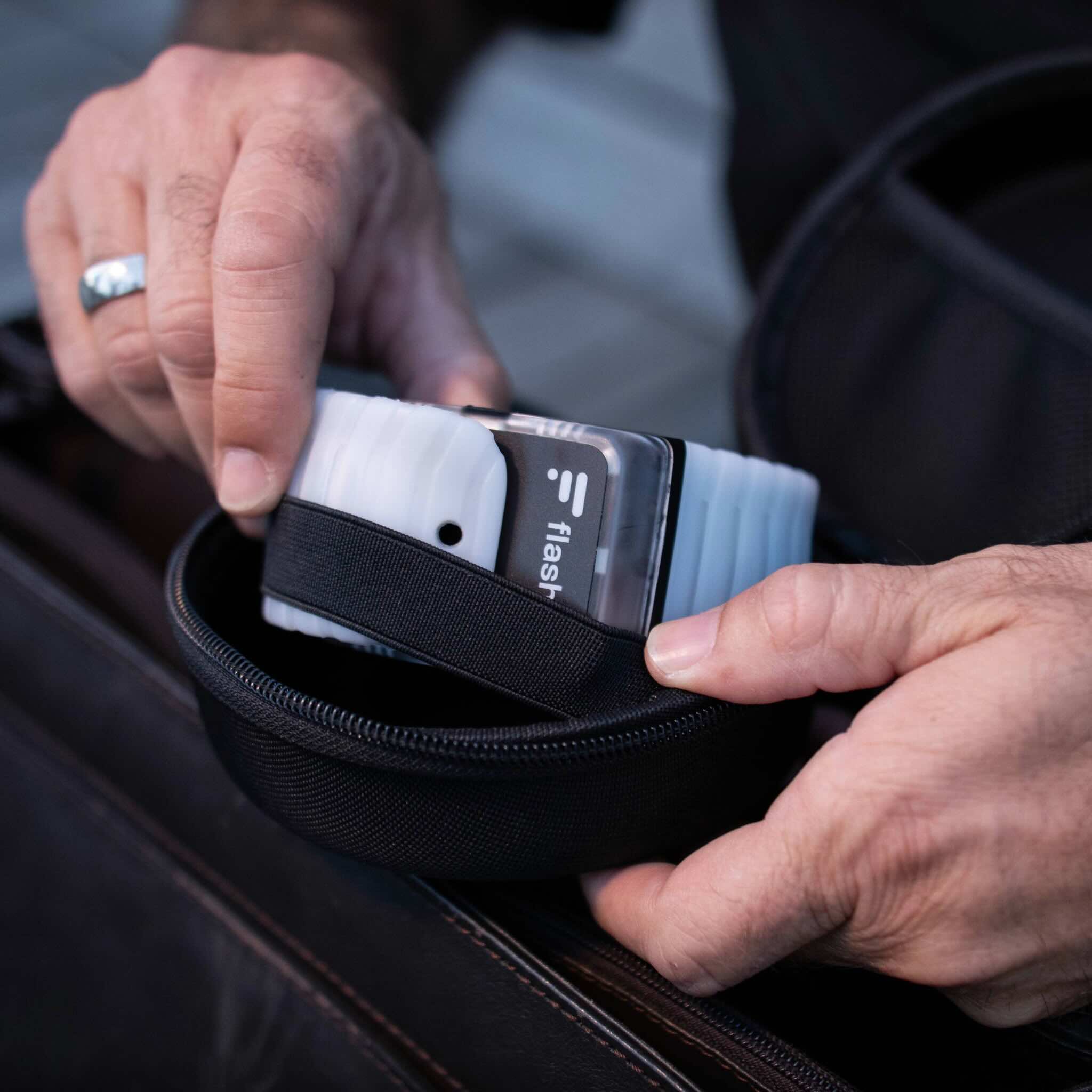 Mann mit silbernem Ehering packt Flasher Armbänder aus der Flasher Schutzhülle aus.