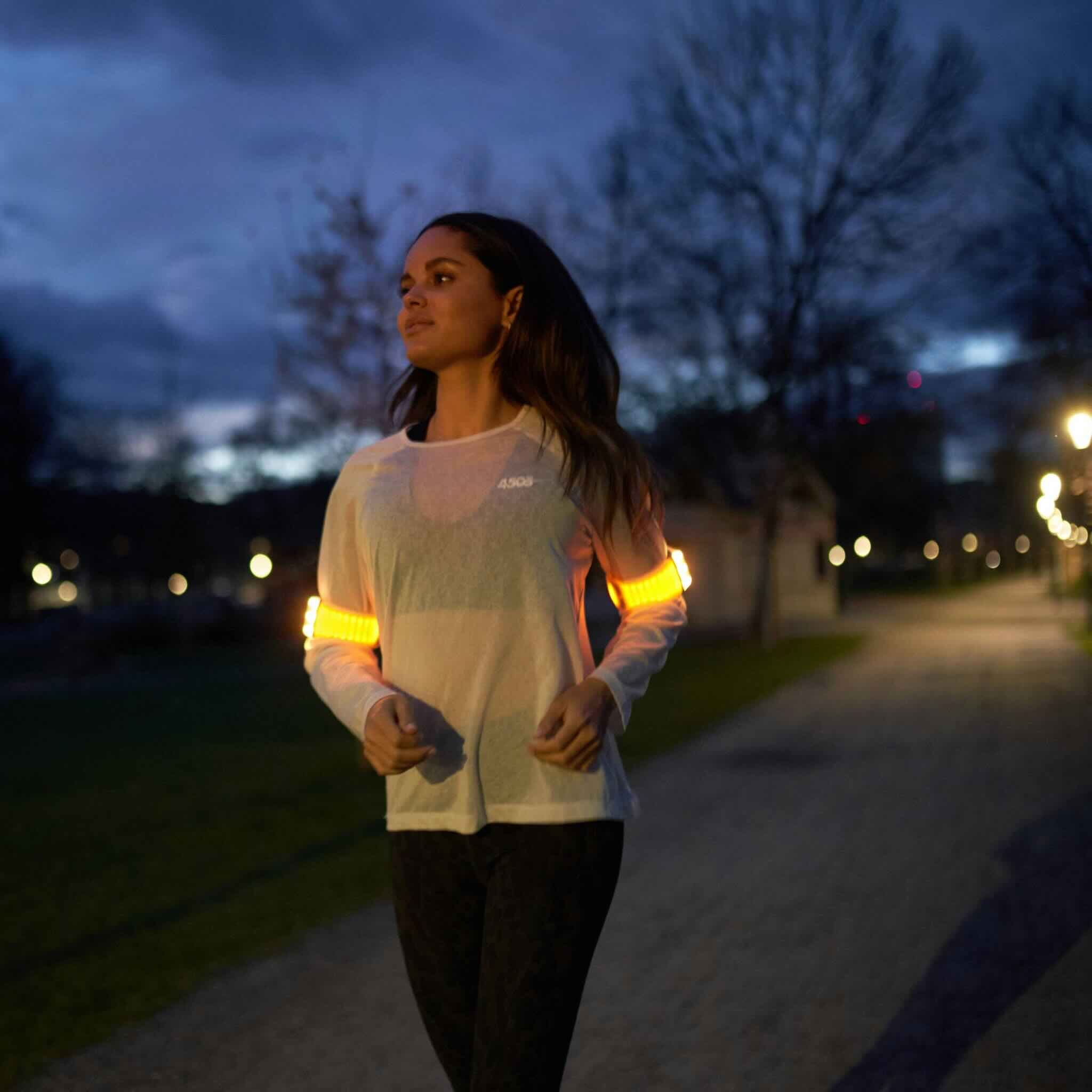 Junge Läuferin mit Flasher im gelben Joggingmodus abends.