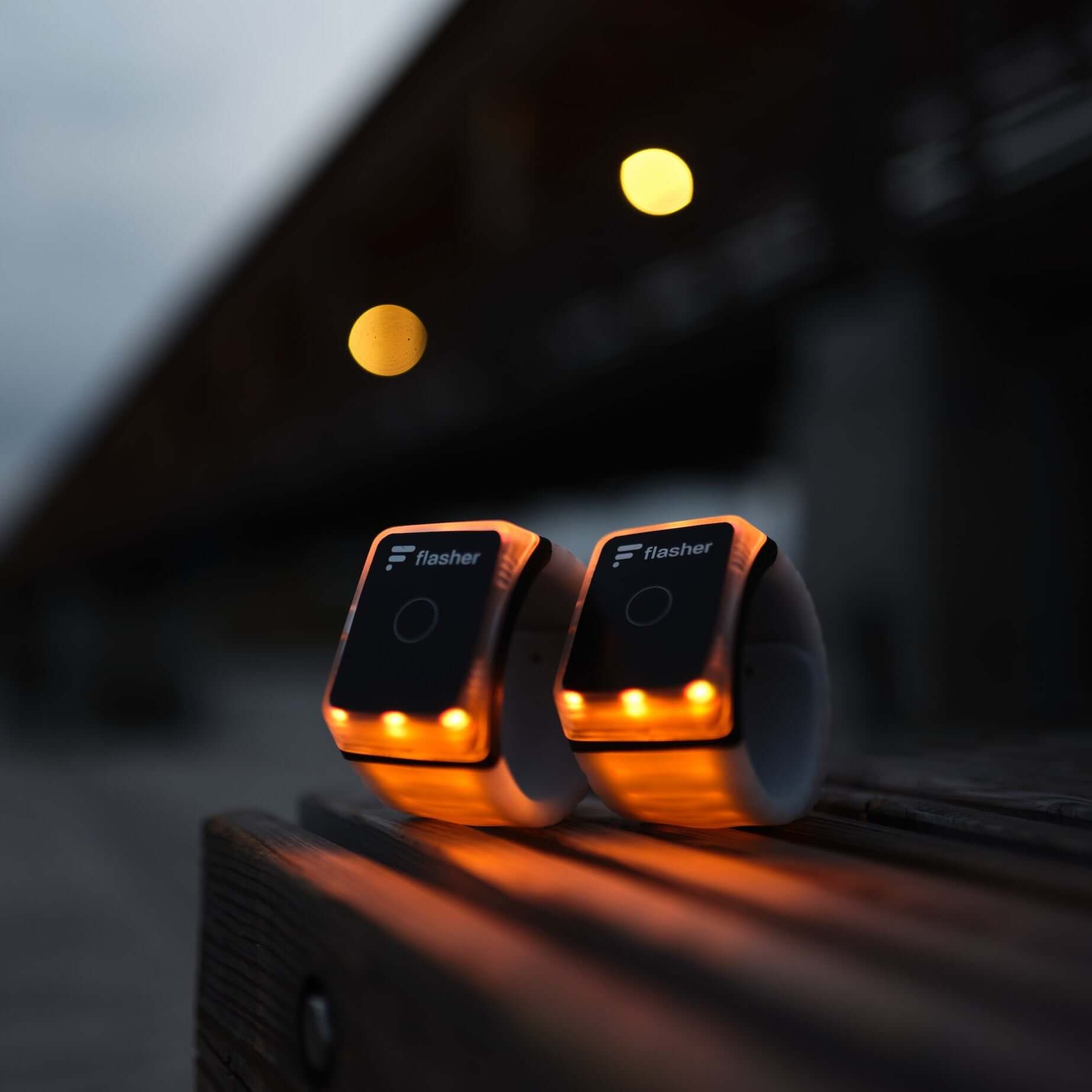Flasher Set aus zwei Armreifen im Jogging Mode, beide orange leuchtend, in eingerollter Form.