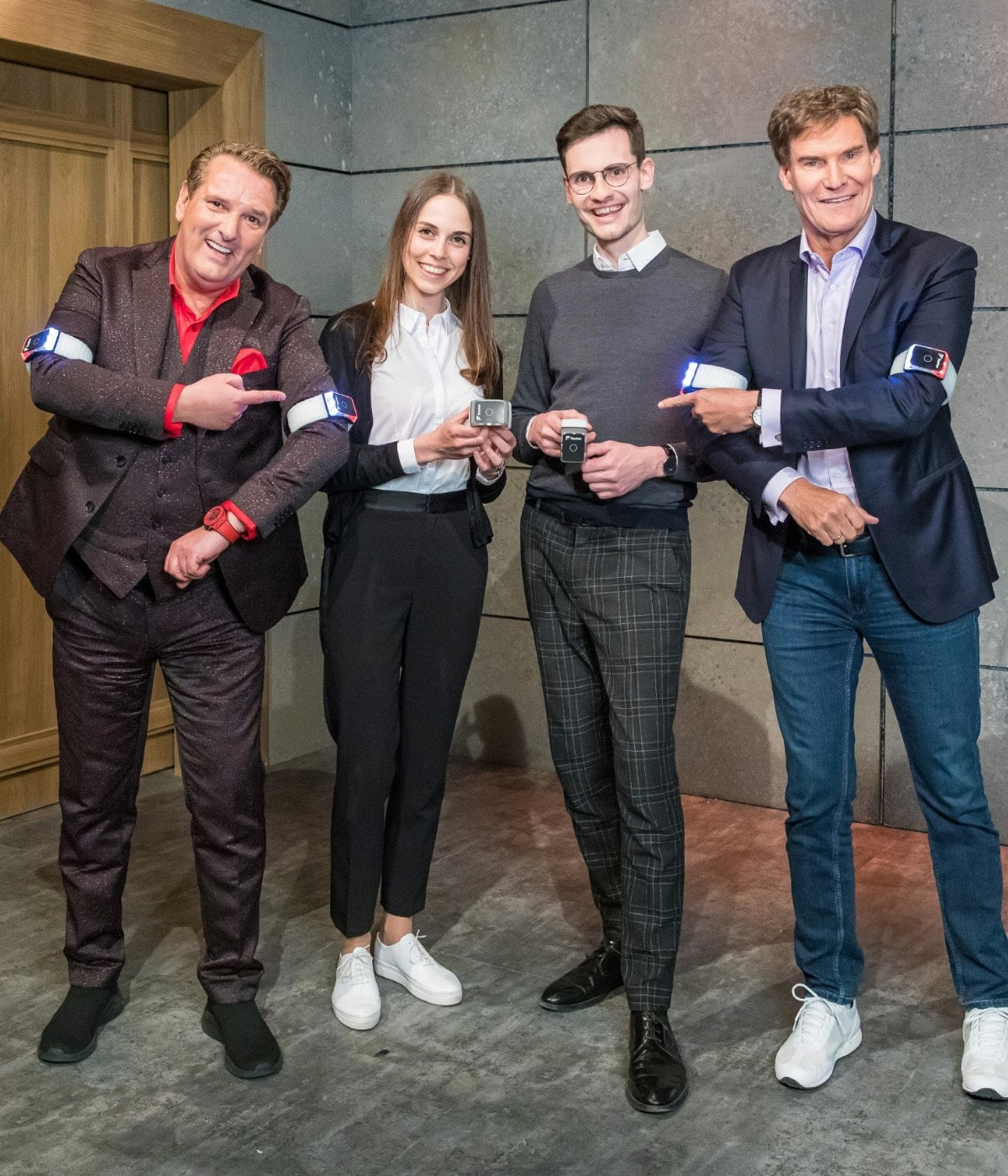 Von rechts nach Links: Ralf Dümmel, Ines Wöckl, Alexander Rech, Carsten Maschmeyer, alle mit Flasher Armbändern in der Höhle der Löwen, lachend.
