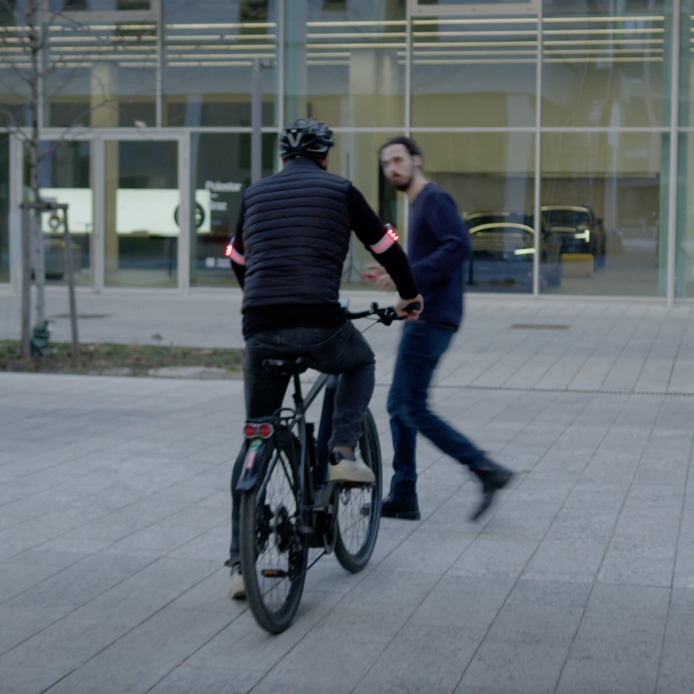 Radfahrer bremst vor Fußgänger, das Bremslicht der Flasher Armbänder leuchtet rot auf.