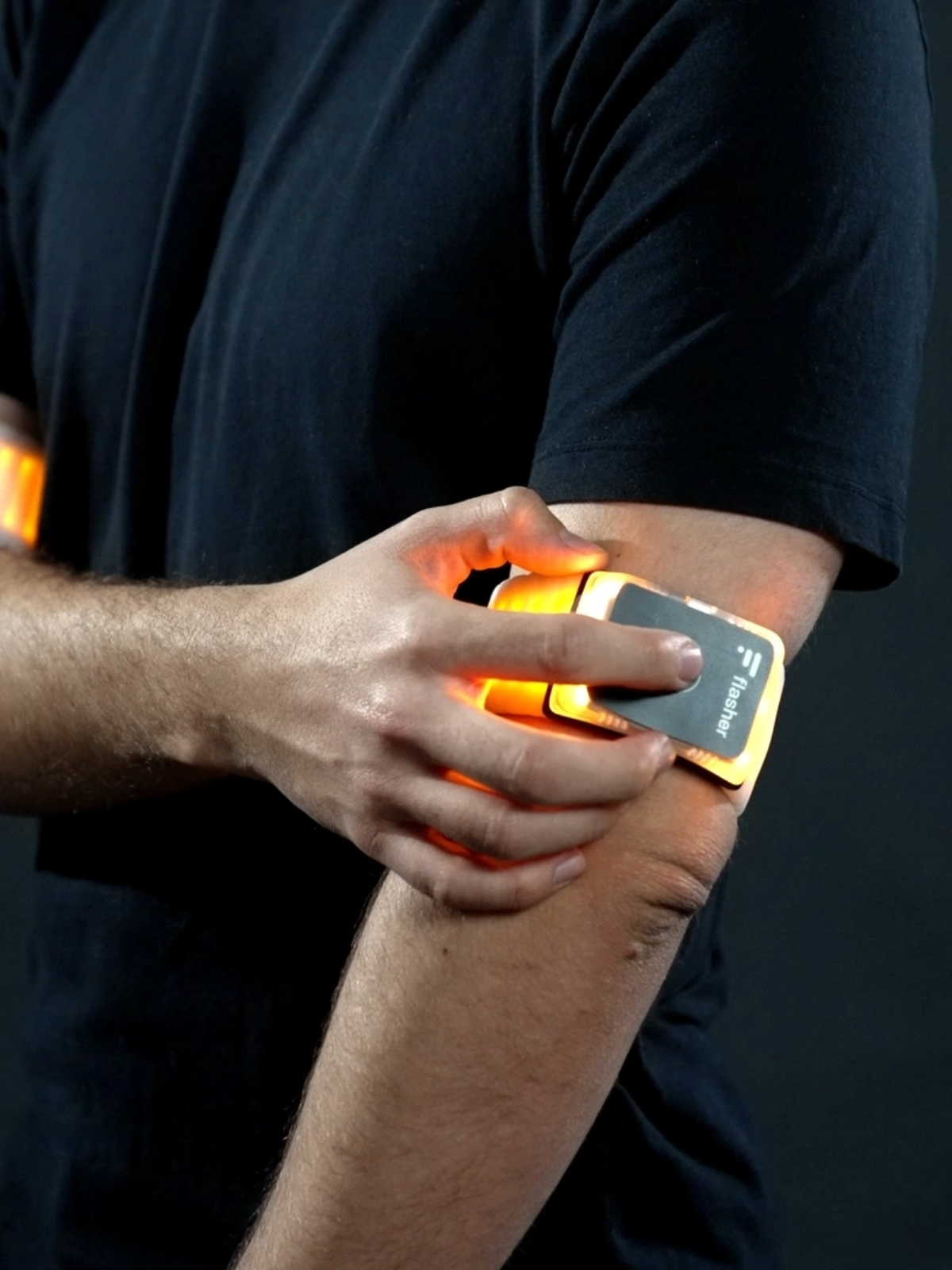 Person hält den Knopf eines Flasher Armbands lange gedrückt, bis sich das Armband einschaltet. Hier leuchtet es hell gelb.