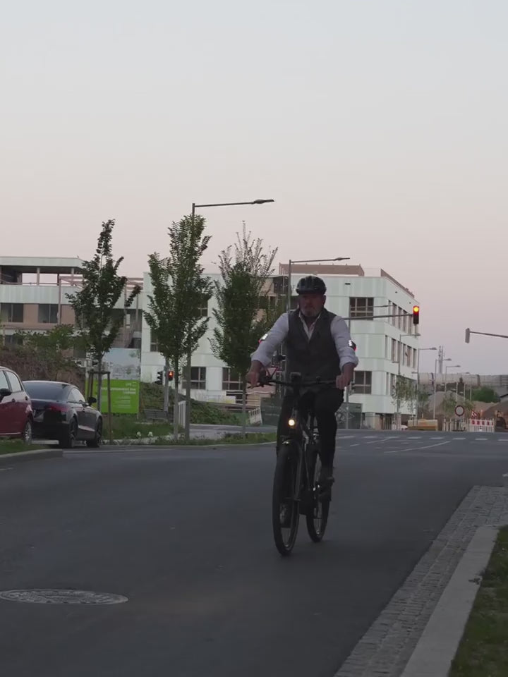 Radfahrer schwenkt Elbogen zur Seite, aktiviert Flasher Blinker und biegt stabil links ab.