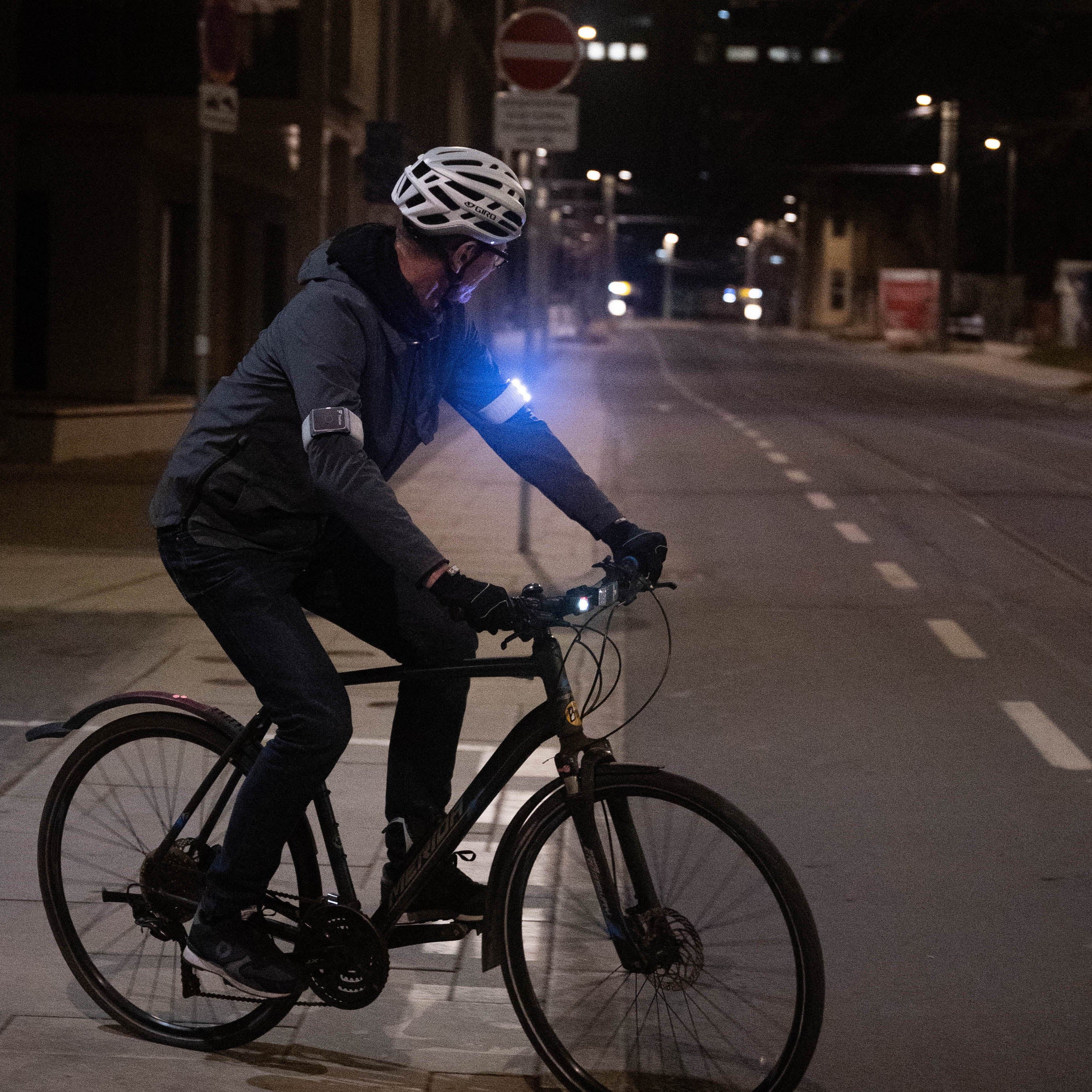 Radfahrer nachts mit Flasher, der Straßenschilder ansieht.