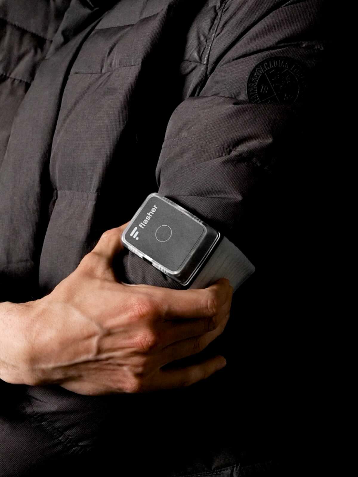 Person in dicker Daunenjacke schnappt Flasher Armband leicht über den Oberarm.