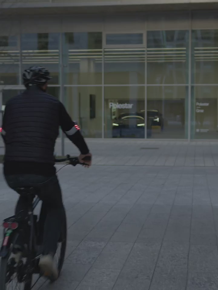 Radfahrer bremst, das Flasher Bremslicht leuchtet rot. Bei Tag und bei Nacht.